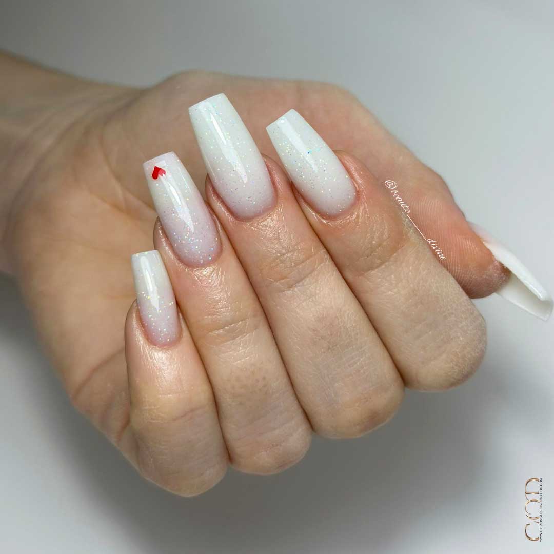 Photos d'ongles carré long milky white pailleté avec nail art coeur rouge sur l'index