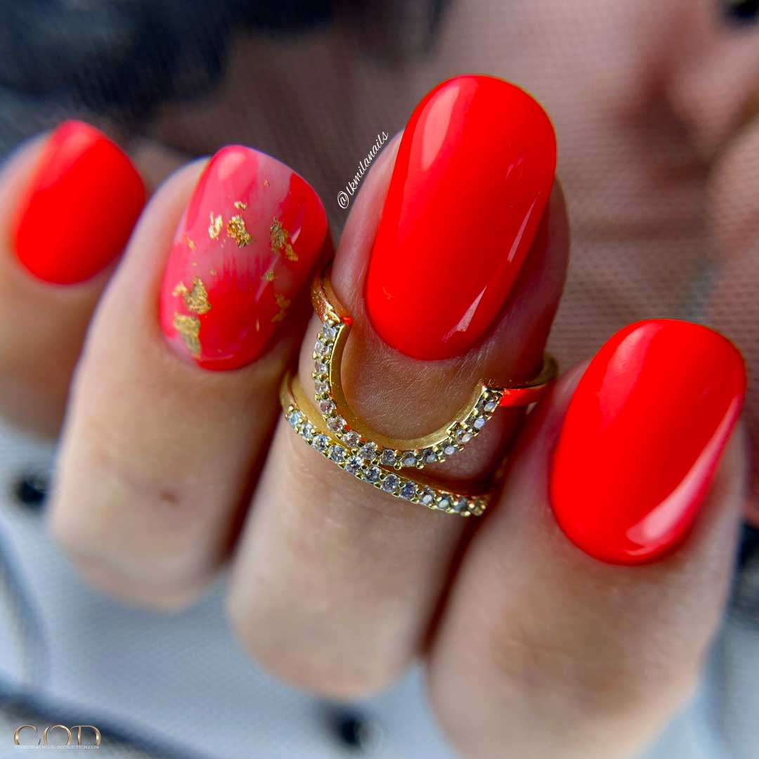 Photo pose d'ongle courts néon orange foncé avec nail art feuille d'or